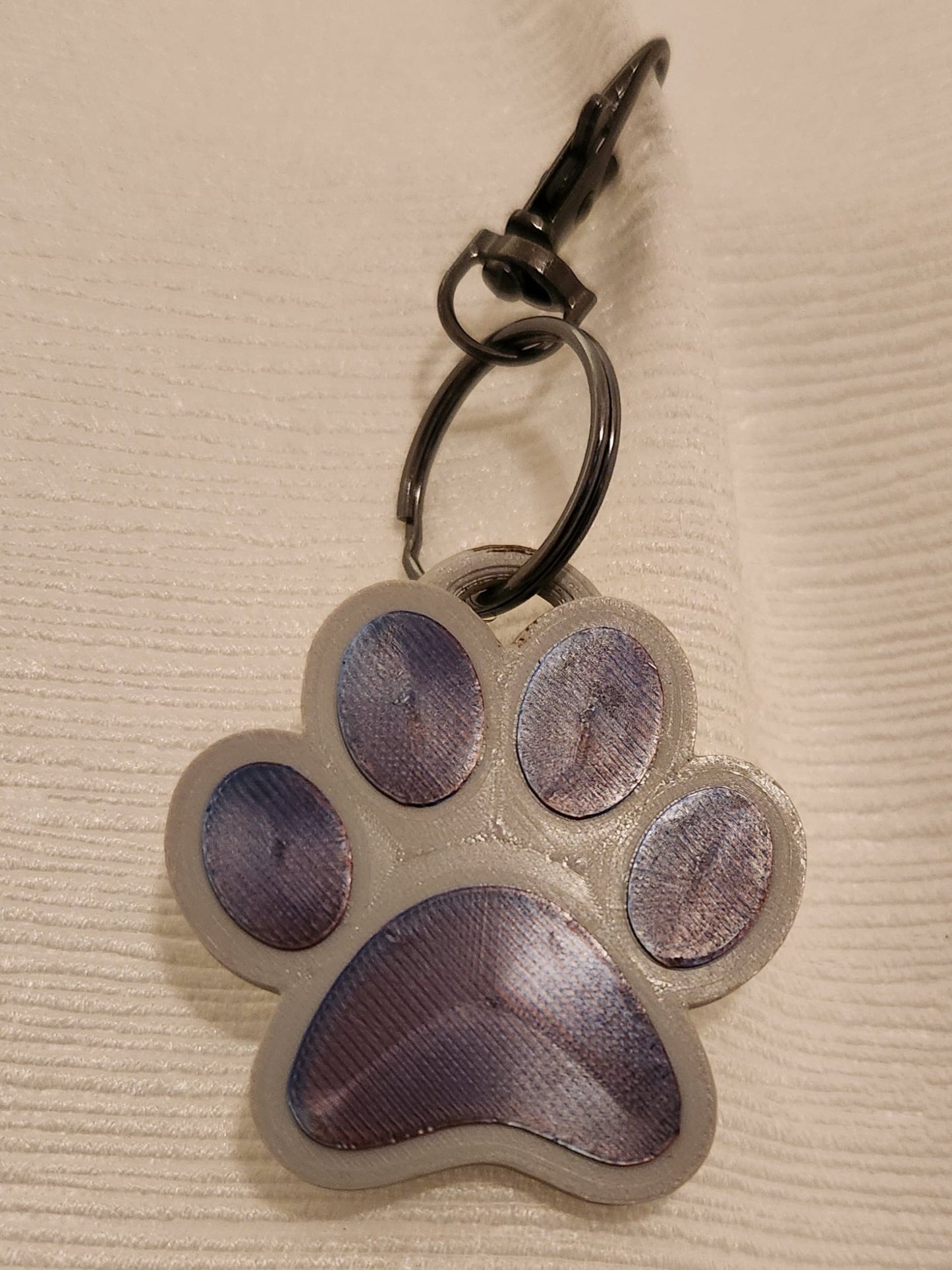 The keychain is printed on a 3-D printer by the local vendor, Imaginative Printing. The keychain in your box may be of any color variation.